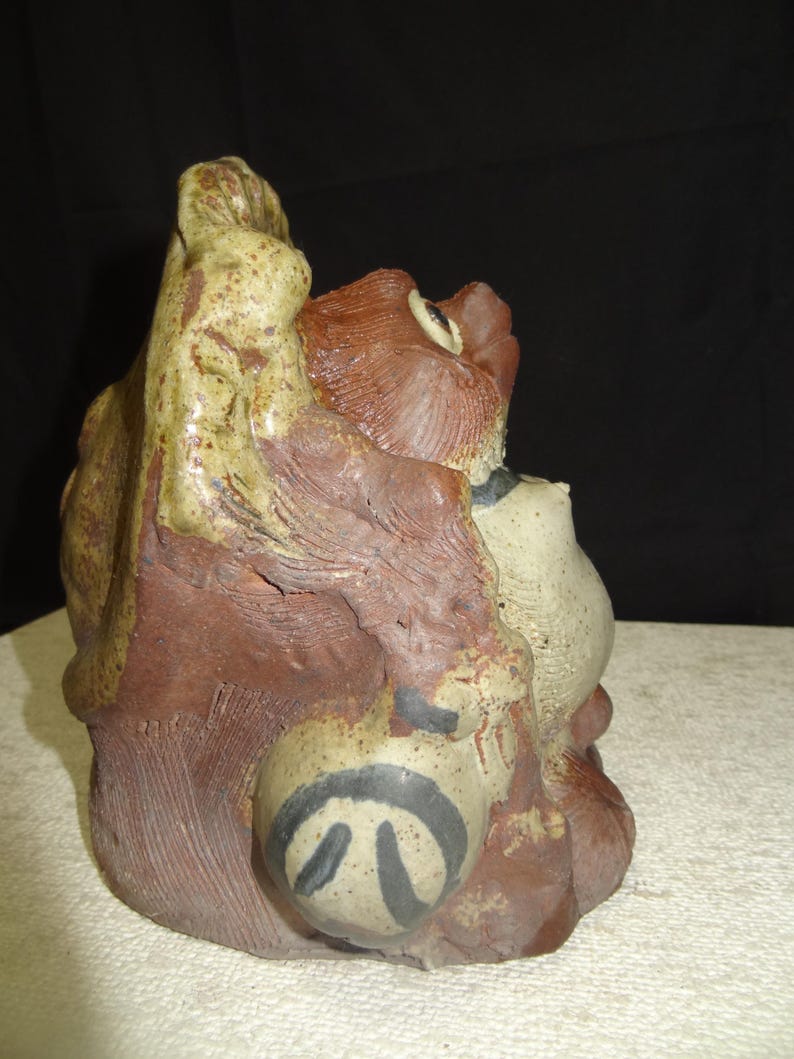 May include: A ceramic sculpture featuring a stylized animal figure. The sculpture is primarily brown and beige with black accents. The figure has a textured surface and a unique, abstract design.