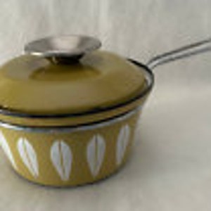 Może przedstawiać: Żółty emaliowany garnek z białym wzorem liści i srebrną pokrywką i uchwytem.