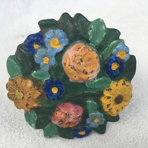 May include: A cast iron door knocker shaped like a bouquet of flowers. The flowers are painted in shades of yellow, orange, pink, blue, and green.