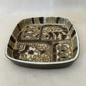 May include: Square ceramic dish with a brown and beige patterned design. The dish has a dark brown rim and a white border. The interior features four distinct sections with stylized floral and abstract motifs. A decorative piece for serving or display.