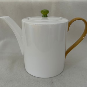 May include: White ceramic teapot with a green knob on the lid and a yellow handle.