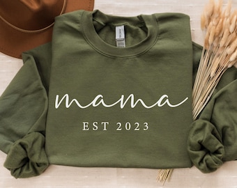 May include: A green sweatshirt with the text "mama est 2023" in white.