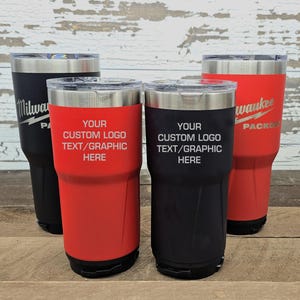 May include: Four insulated tumblers in black and red with silver rims and clear lids. Two tumblers have the text "YOUR CUSTOM LOGO TEXT/GRAPHIC HERE" in white. The other two tumblers have the text "Milwaukee PACKOUT" in white.