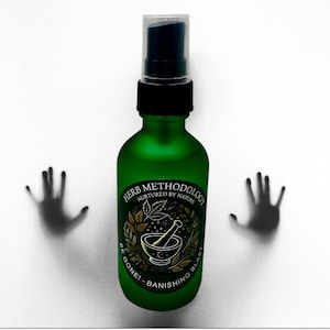May include: A green glass bottle with a black pump and a clear cap. The bottle has a label with the text "HERB METHODOLOGY" and "BE GONE! - BANISHING BLAST". Silhouetted hands are on either side of the bottle.