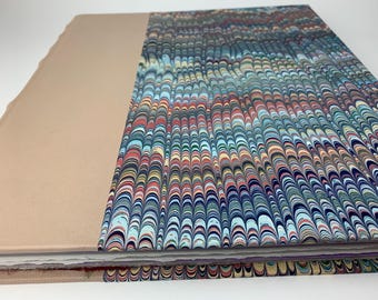 May include: A handmade book with a marbled paper cover. The cover features a swirling pattern of blue, green, red, and yellow.