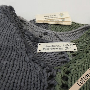 May include: Hand-knitted gray and green cotton twill sweater with a label that reads "Hand Knit by Pam Parenteau".