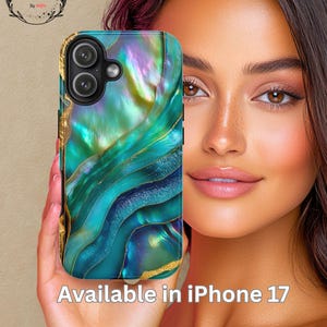 Puede incluir: Funda de teléfono inteligente con un diseño iridiscente en espiral en tonos de verde azulado, dorado y morado. La funda tiene un recorte para la cámara y el texto "Available in iPhone 17". La funda se sostiene en una mano.