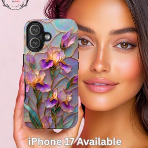 May include: A smartphone case featuring a stained-glass design with purple and gold iris flowers. The case has a pearlescent background and the text "iPhone 17/Available". The case is held in a hand.