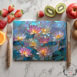 May include: A rectangular cutting board with a stained glass lotus flower design in shades of pink, blue, and gold. The board is surrounded by fresh fruit, including strawberries, kiwi, and an apple. A fork and knife are placed on either side.