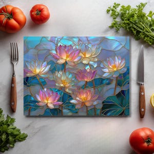 May include: A rectangular cutting board with a stained glass design featuring lotus flowers in shades of pink, yellow, and white, with blue and green leaves. The background is a mosaic of blue and gold. A fork, knife, tomatoes, and parsley are on the sides.