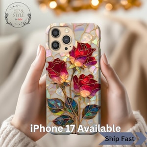 May include: A phone case with a stained glass effect, showcasing three red roses and green leaves. The case has a shimmering background and the text "iPhone 17 Available". The case is held in two hands.