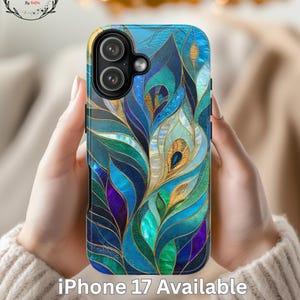 Può includere: Custodia blu per iPhone 17 con un design a piume di pavone nei toni del blu, verde, oro e viola. La custodia ha una finitura lucida e presenta il testo "iPhone 17 Available".