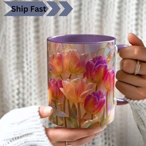Può includere: Una tazza in ceramica con interno e manico viola, caratterizzata da una vivace illustrazione di tulipani rosa, arancioni e gialli in stile vetrata. Il design presenta contorni dorati e riflessi iridescenti su tutto il motivo floreale.