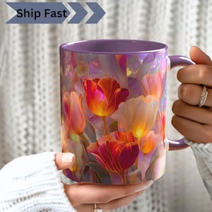 May include: A ceramic mug featuring a vibrant stained glass pattern of red, orange, and yellow tulips. The mug has a solid purple handle and interior rim. The exterior surface displays a colorful floral design with dark outlines.