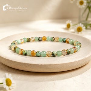 Könnte beinhalten: Ein Armband mit grünen, gelben und klaren Edelsteinperlen. Das Armband liegt auf einem hellen Holztablett. Der Text "SJ Design Diaries Healing Crystals" ist im Bild zu sehen.