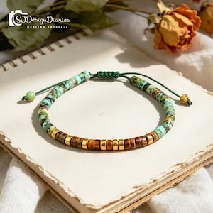 May include: A beaded bracelet featuring turquoise and brown stones, accented with gold-colored beads. The bracelet is strung on a green cord with an adjustable knot closure. The text "SJ Design Diaries HEALING CRYSTALS" is visible in the upper left corner.
