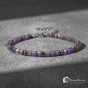 May include: A beaded bracelet featuring alternating purple disc-shaped beads and small metallic dark grey spacer beads. The bracelet includes a silver-toned metal lobster claw clasp and an adjustable chain link extension at the end.