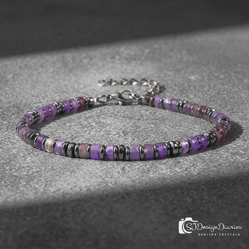 May include: A beaded bracelet featuring alternating purple disc-shaped beads and small metallic dark grey spacer beads. The bracelet includes a silver-toned metal lobster claw clasp and an adjustable chain link extension at the end.