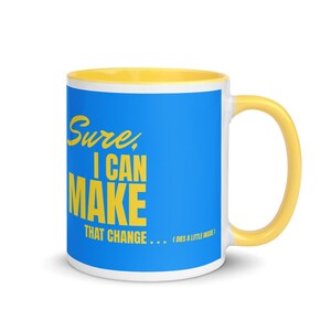 May include: A white ceramic mug with a blue exterior and yellow interior and handle. The mug features the text "Sure, I can make that change... (dies a little inside)" in yellow.