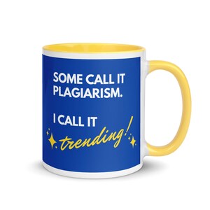 May include: A white ceramic mug with a yellow interior and handle. The mug features the text "SOME CALL IT PLAGIARISM. I CALL IT trending!" in white and yellow on a blue background. The mug has a glossy finish.
