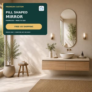May include: A frameless pill-shaped mirror mounted on a beige wall above a floating wooden vanity with a white basin sink. The mirror reflects a window and a green plant. Text on the image reads: PREMIUM CUSTOM PILL SHAPED MIRROR.