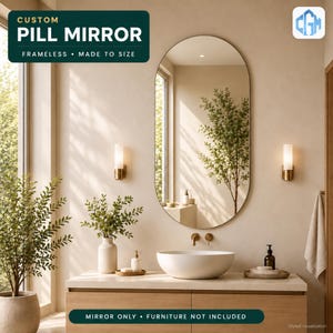 May include: A frameless pill-shaped mirror with a reflective surface. The mirror is displayed in a bathroom setting with text that reads CUSTOM PILL MIRROR FRAMELESS MADE TO SIZE and MIRROR ONLY FURNITURE NOT INCLUDED.