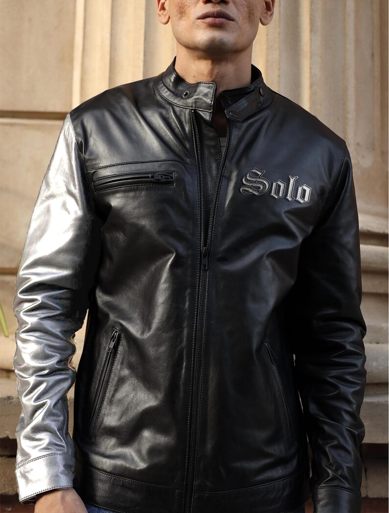 May include: Black leather jacket with silver sleeves and the word "Solo" embroidered on the chest. The jacket features a zippered front, a small zipped pocket, and a stand-up collar. The sleeves are a metallic silver colour.