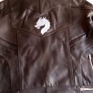 May include: A black leather jacket featuring a white dragon emblem on the back. The jacket has a classic biker design with zip closures and a tailored fit. The leather appears smooth, and the stitching is visible.