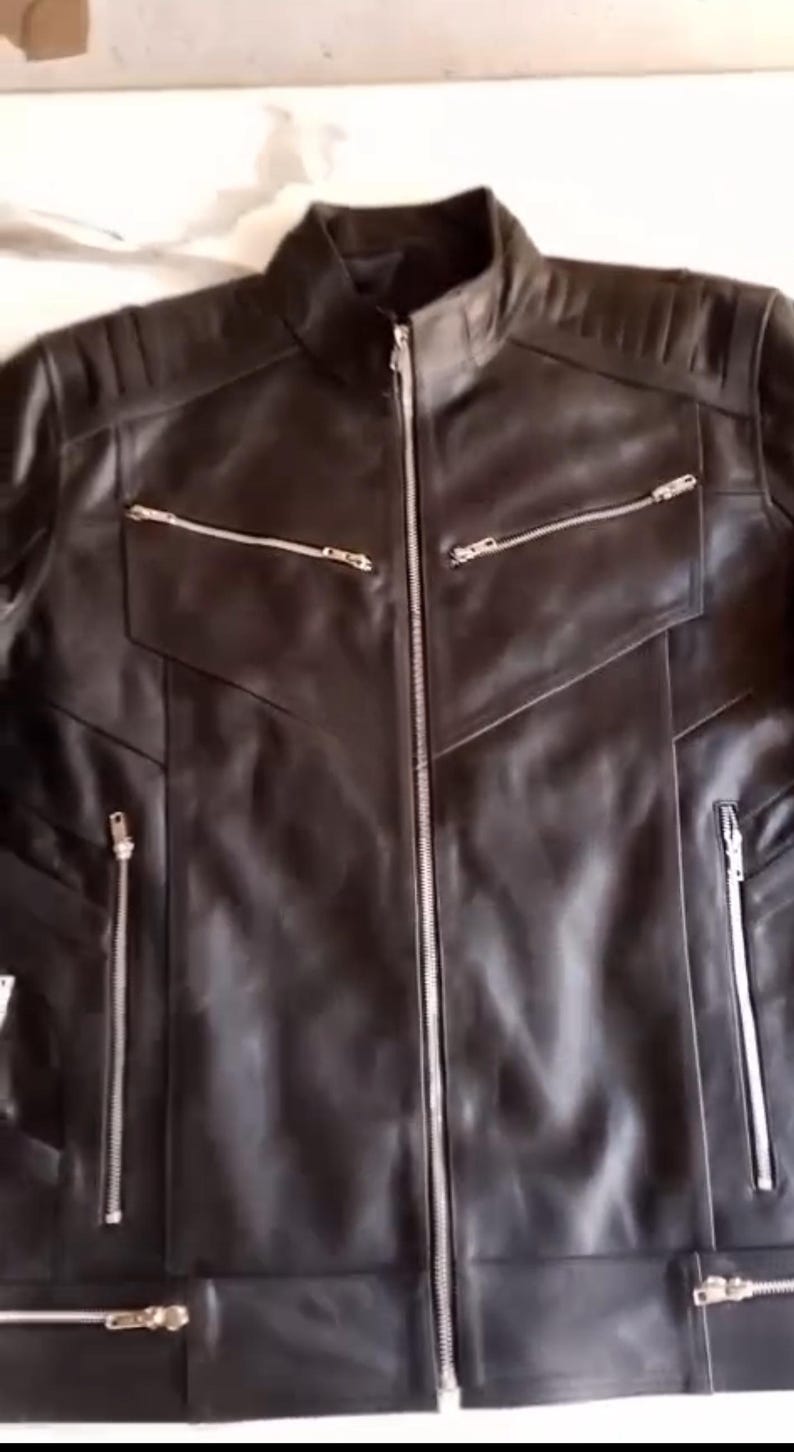 May include: Black leather jacket with a stand-up collar and multiple zipped pockets. The jacket features a front zip closure and quilted shoulder detailing. A classic outerwear piece.