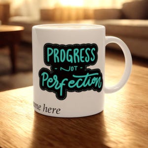 May include: White ceramic mug with a black and turquoise design that says "Progress - not - Perfection".
