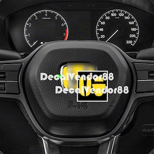 May include: Close-up of a black steering wheel with a yellow logo and the text "DecalVendor88". The dashboard gauges are visible in the background. The speedometer reads 0 mph.