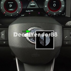 May include: A black steering wheel with a silver trim and a black and white carbon fiber decal on the center. The decal has the text "DecalVendor88" on it.