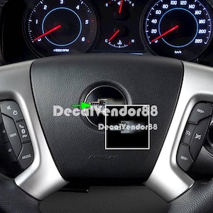 May include: A black and silver car steering wheel with a black carbon fiber decal in the center. The decal has the text "DecalVendor88" printed on it.