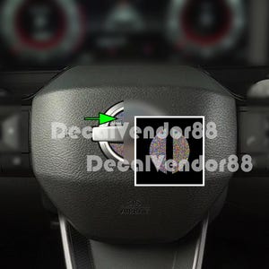 May include: Close-up of a black steering wheel with a silver accent. The wheel has a circular emblem with a colorful, speckled design. The text "DecalVendor88" is visible.
