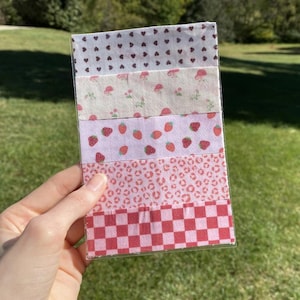 Puede incluir: Una colección de cintas adhesivas decorativas washi con varios patrones. Las cintas presentan diseños que incluyen corazones, setas, fresas, estampado de leopardo y un tablero de ajedrez rojo y blanco. Las cintas se guardan en una funda de plástico transparente.