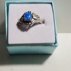 May include: A silver ring with a blue opal gemstone set in a leaf design.