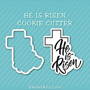 K&ouml;nnte beinhalten: Ein Ausstecher in Form eines Kreuzes mit den Worten "He is Risen" in einer stilisierten Schriftart. Der Ausstecher ist wei&szlig; und die Worte sind schwarz.
