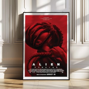 Puede incluir: Póster de la película "Alien: Romulus" enmarcado en un marco negro. El póster presenta una imagen roja y negra de una criatura con el título de la película y la fecha de lanzamiento. El póster está apoyado contra una pared blanca.