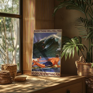 May include: A framed poster with a vintage surfing theme. The poster features the text "EVERYTHING WILL KILL YOU SO CHOOSE SOMETHING FUN" above and below a depiction of surfers riding a large wave. The poster is displayed on a wooden surface.