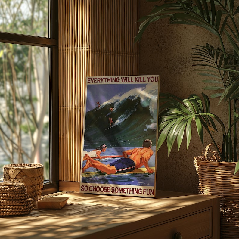 May include: A framed poster with a vintage surfing theme. The poster features the text "EVERYTHING WILL KILL YOU SO CHOOSE SOMETHING FUN" above and below a depiction of surfers riding a large wave. The poster is displayed on a wooden surface.