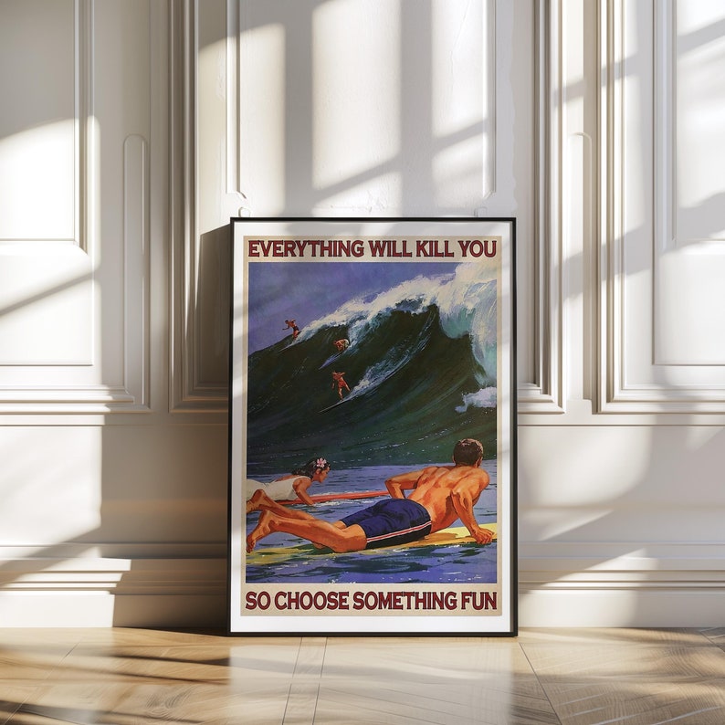 May include: Framed vintage-style poster with the text "EVERYTHING WILL KILL YOU SO CHOOSE SOMETHING FUN." The image depicts surfers riding a large wave. A man and woman are seen in the foreground on surfboards. The poster is in a black frame.