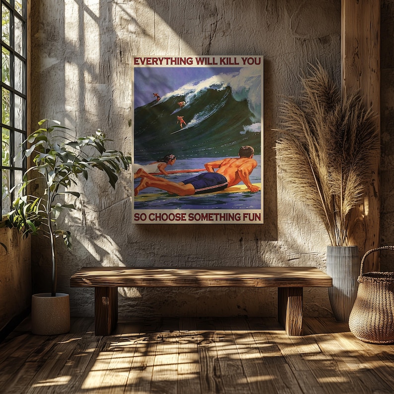 May include: A framed vintage-style poster with a surfing theme. The image depicts surfers riding a large wave, with the text "EVERYTHING WILL KILL YOU SO CHOOSE SOMETHING FUN" in a bold font. The poster is displayed in a room with a wooden bench and plants.