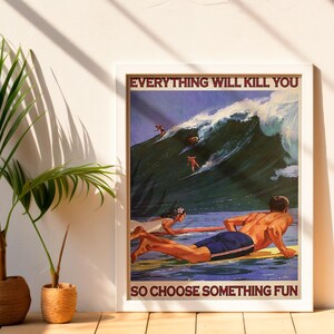 May include: Framed poster with the text "EVERYTHING WILL KILL YOU SO CHOOSE SOMETHING FUN." The image depicts surfers riding a large wave. Two people are on surfboards in the water. A palm plant is to the left of the poster.