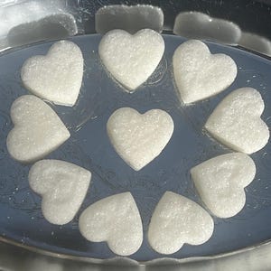 May include: A silver tray with ten white heart-shaped sugar cubes.