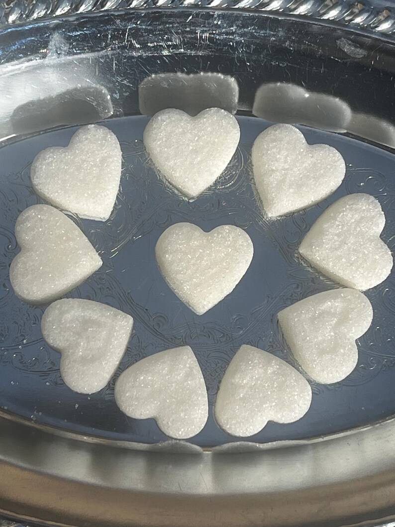 May include: A silver tray with ten white heart-shaped sugar cubes.