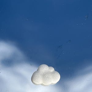 May include: A white sugar cloud shaped cookie on a blue background.