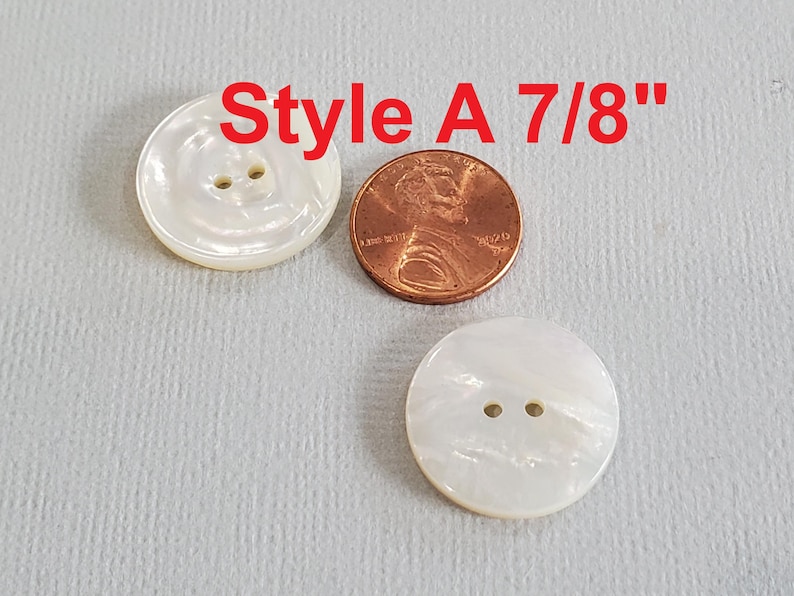 May include: Two white, round buttons with two holes each, next to a penny. The buttons are labeled "Style A 7/8"" in red text.