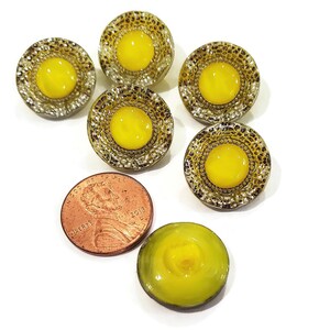Back side of vintage moon glow glass buttons with the molded shank visible. The centers of the buttons are lemon yellow and the rims have a sparkly silver luster.