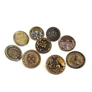 May include: A collection of antique brass buttons with various embossed designs. The buttons feature floral, landscape, and figural motifs in shades of gold, bronze, and silver. The buttons are round and vary in size.