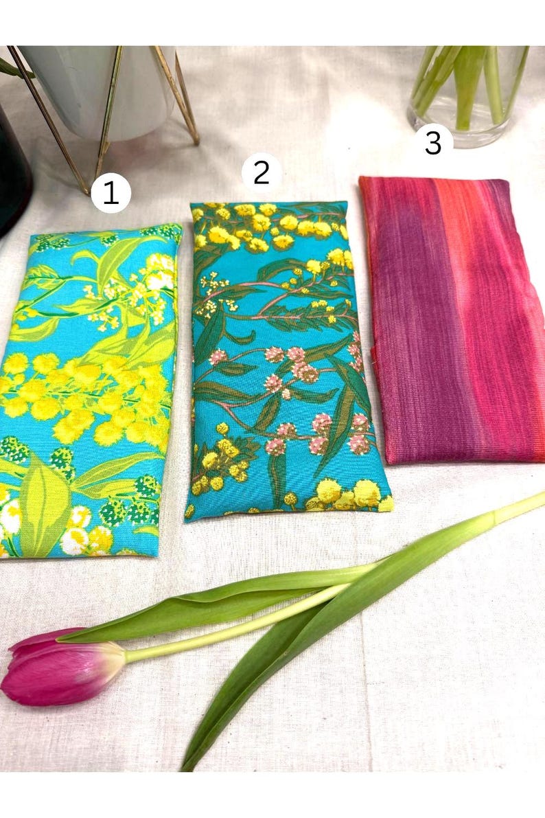 Puede incluir: Tres bolsas rectangulares de tela con estampados florales. Dos bolsas tienen un fondo turquesa con dise&ntilde;os florales amarillos y verdes. La tercera bolsa tiene un estampado tie-dye rosa y morado. Un tulip&aacute;n rosa y hojas verdes en primer plano.